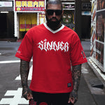 Person wearing a red 'Sinner' t-shirt on a street with urban background