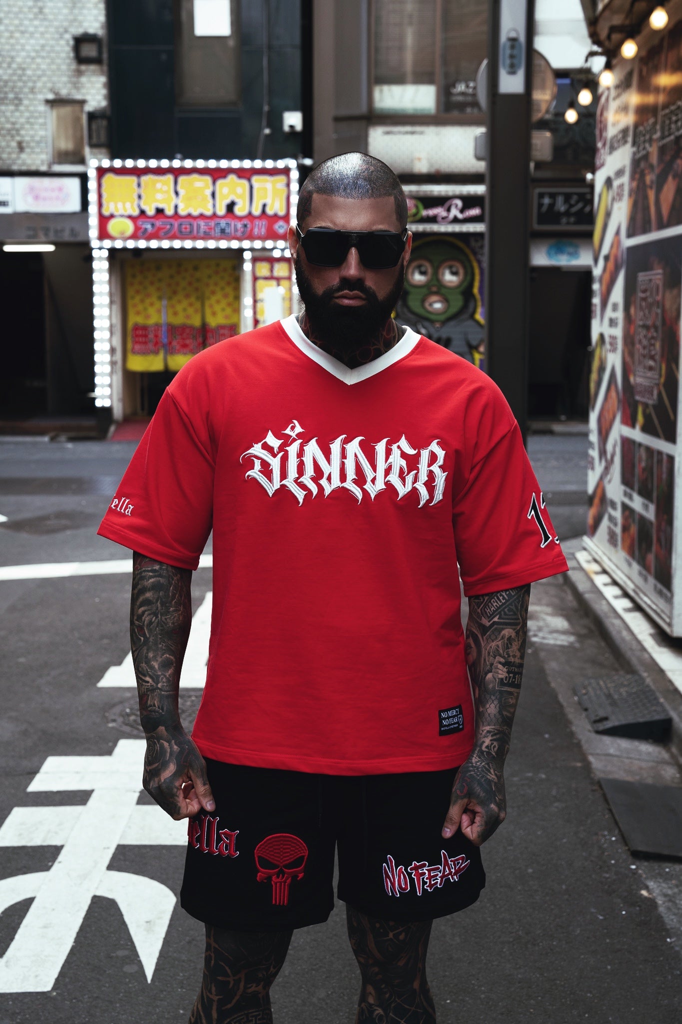 Person wearing a red 'Sinner' t-shirt on a street with urban background