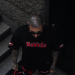 Person wearing a black t-shirt with red text, standing on a dark staircase.