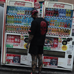 Person interacting with a Coca-Cola vending machine in an urban setting